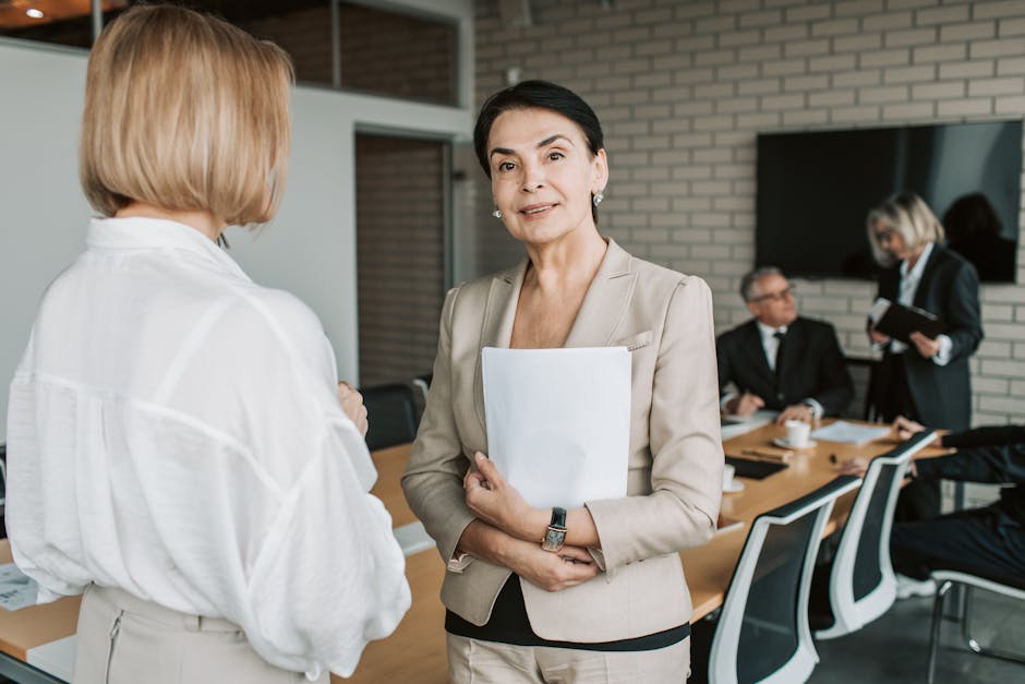 Senior businesswoman smiling and holding documents during a corporate meeting indoors.